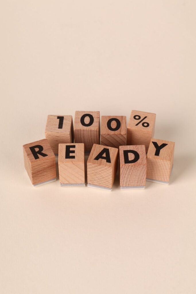 Home Wooden blocks spell out '100% Ready' on a neutral background, symbolizing preparation.